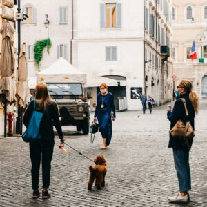 Personne promenant son chien en laisse dans une rue de ville pendant la pandémie de Covid-19, masque chirurgical sur le visage