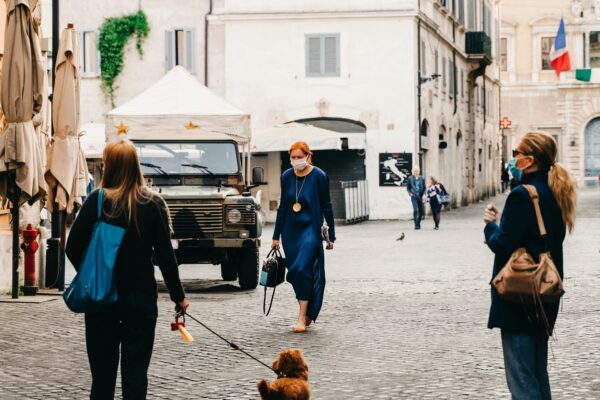 Personne promenant son chien en laisse dans une rue de ville pendant la pandémie de Covid-19, masque chirurgical sur le visage