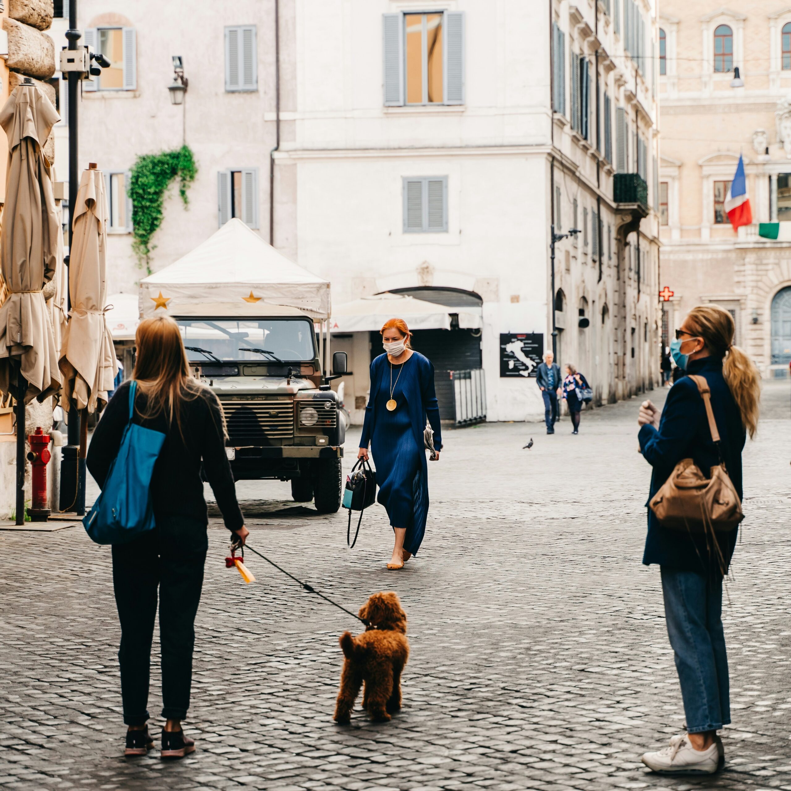 Personne promenant son chien en laisse dans une rue de ville pendant la pandémie de Covid-19, masque chirurgical sur le visage